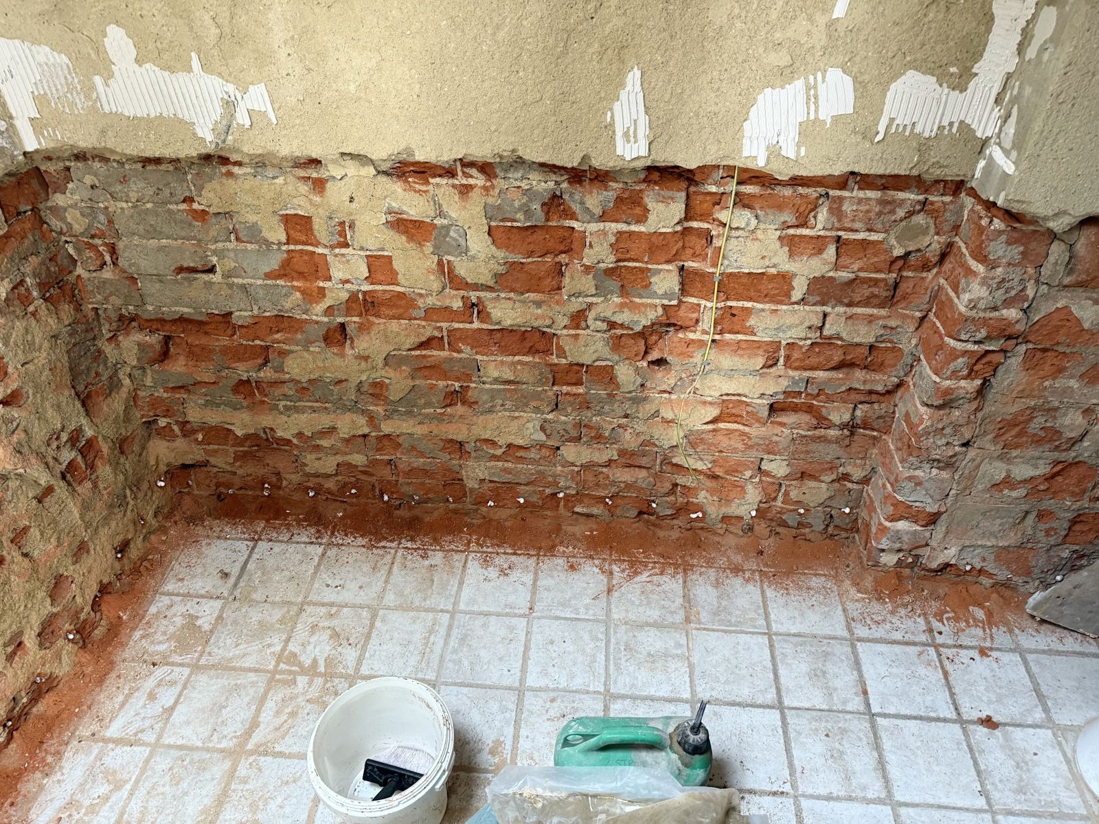 Plaster removed back to bare brick along the base of a wall