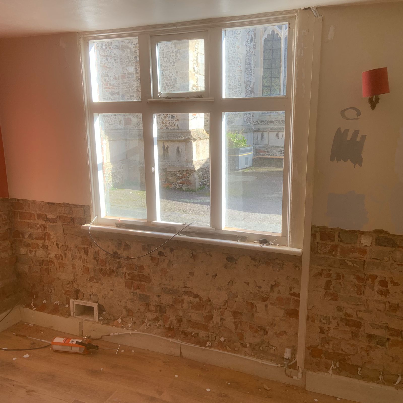 A period room with the plaster stripped to brick below the window