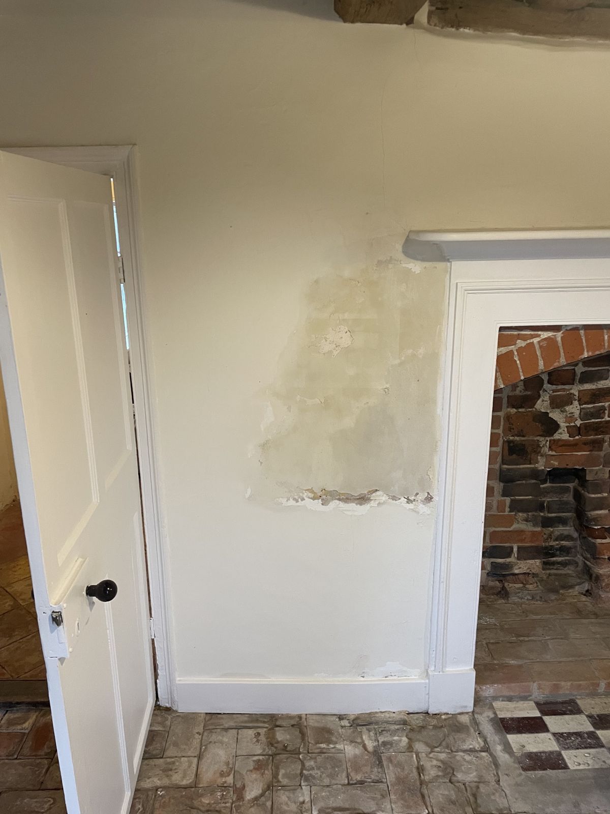 Blown plaster and a damp patch beside a fireplace